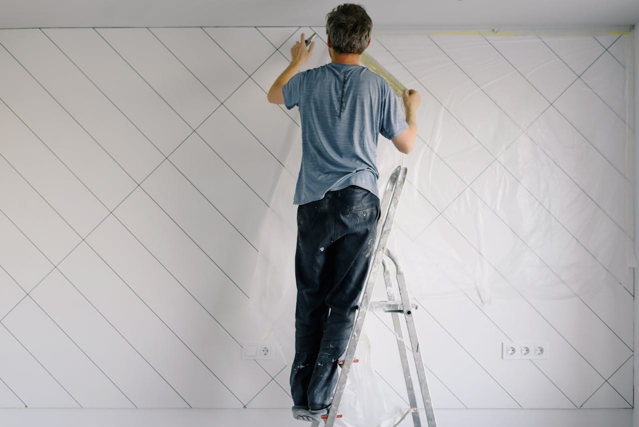 about-02 Adult man painting wall indoors during a home renovation project.