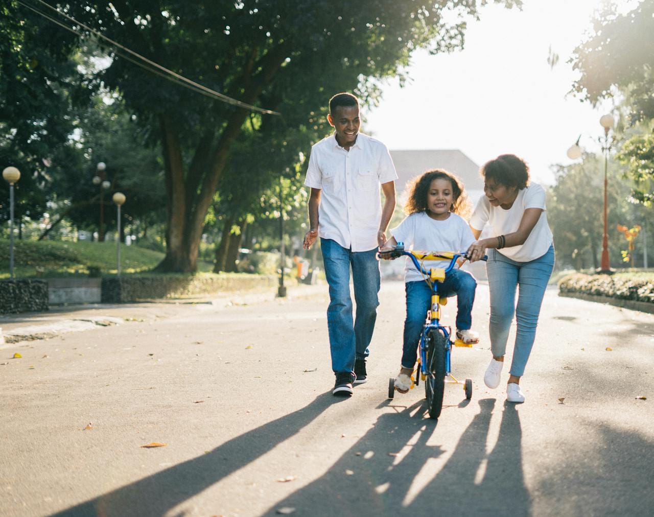 missions-02 Happy family teaching their child to cycle on a sunny day outdoors.